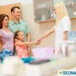 Female dentist shaking hands with young girl whose parents stand behind her